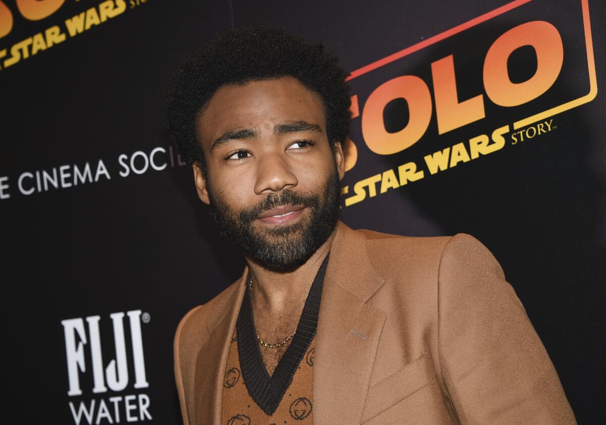 Donald Glover wears a brown blazer and shirt as he arrives at a movie screening