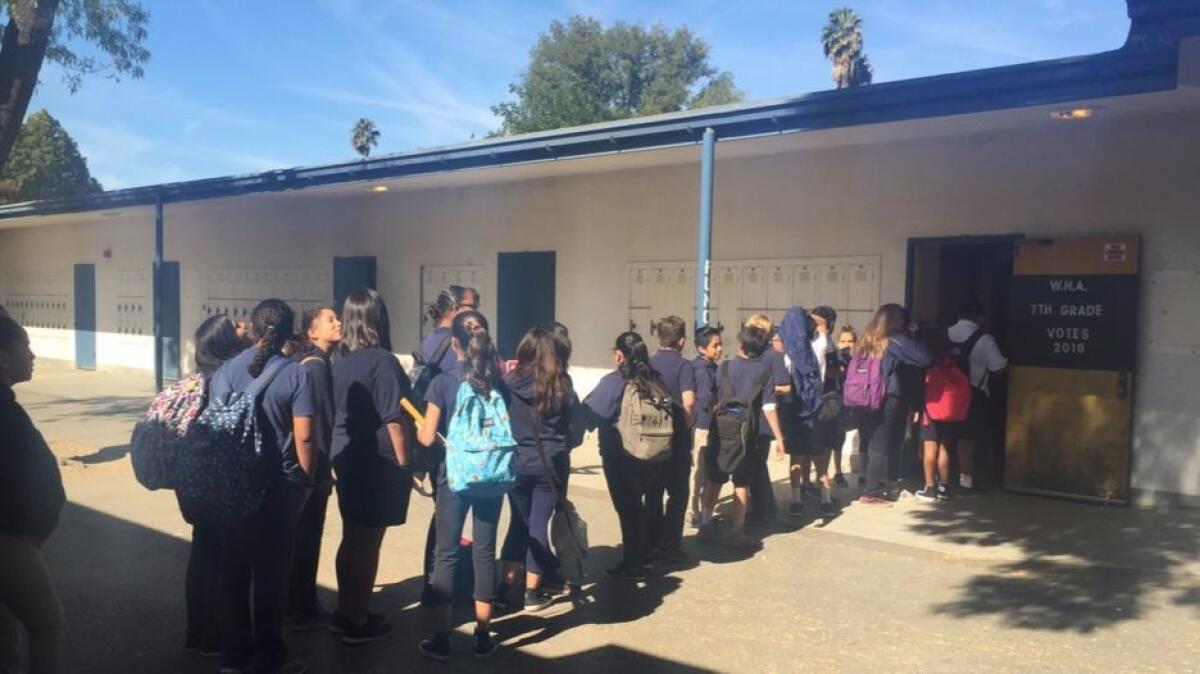 Students at Woodland Hills Academy line up outside their classroom to vote in a mock election.
