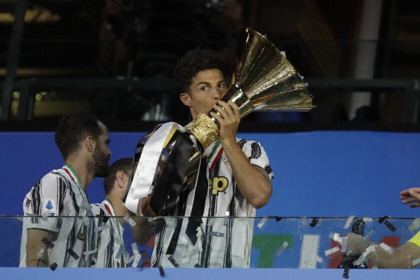 Juventus' Cristiano Ronaldo kisses the trophy as Juventus players celebrate winning an unprecedented ninth consecutive Italian Serie A soccer title, at the end of the a Serie A soccer match between Juventus and Roma, at the Allianz stadium in Turin, Italy, Saturday, Aug.1, 2020. (AP Photo/Luca Bruno)
