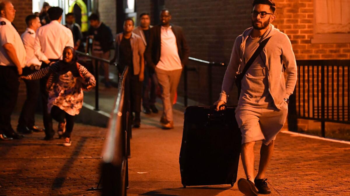 Residents leave the Taplow Tower residential block on the Chalcots Estate in north London. The building was evacuated because of fire safety concerns.