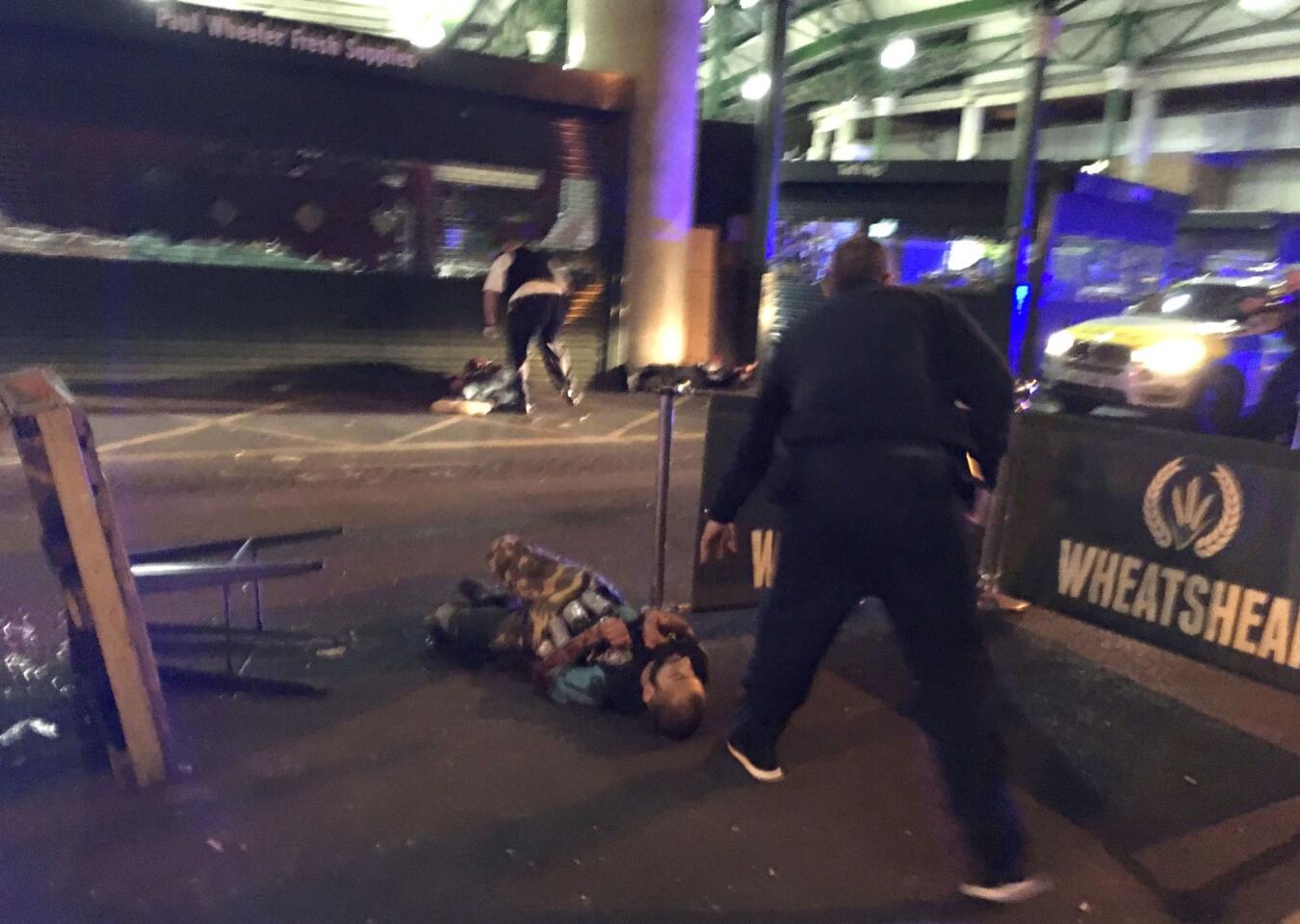 Armed police stand over two suspects shot at the scene of the terror attack outside Borough Market in central London.