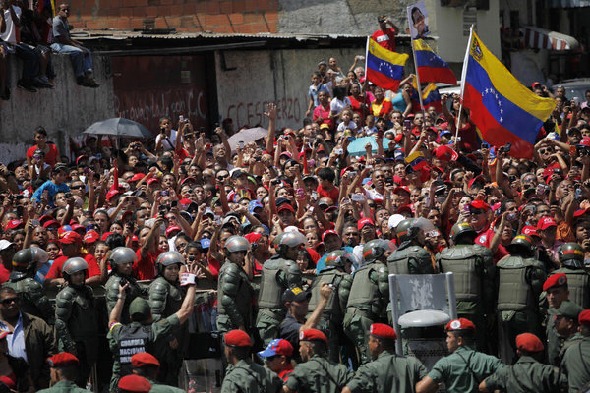 Supporters of late Venezuelan President Hugo Chavez crowd a street in Caracas to watch his coffin pass by as it is taken from the hospital where he died Tuesday. The coffin will be placed at a military academy where it will remain until his funeral.