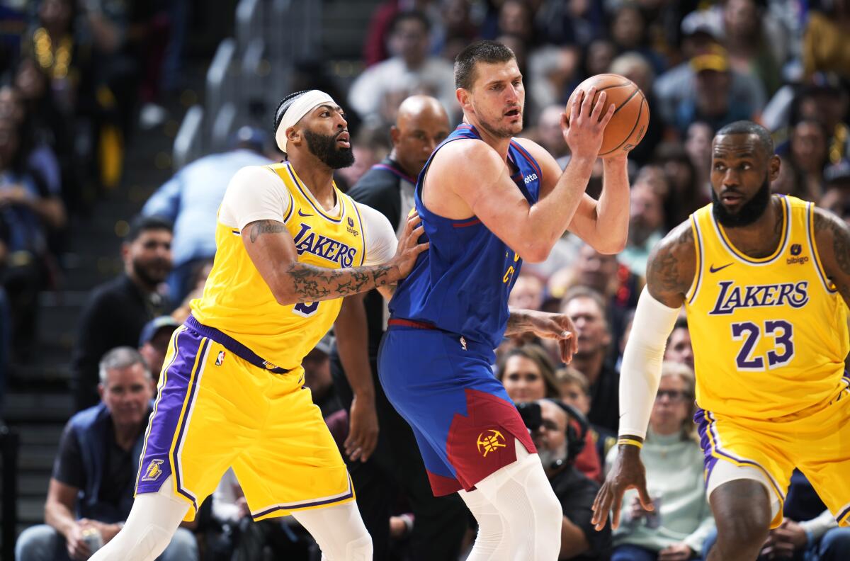 Denver Nuggets center Nikola Jokic looks to pass the ball as Lakers forwards Anthony Davis and LeBron James defend.