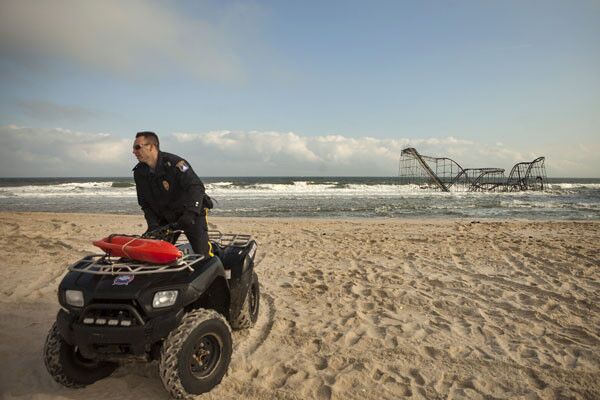 A Seaside Heights, N.J., police officer patrols the beach near a roller-coaster that sits in the water almost six weeks after Superstorm Sandy wrecked a pier.