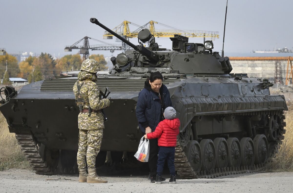 Soldiers of Kyrgyz army stand at checkpoint on city street in Bishkek, Kyrgyzstan, Saturday, Oct. 10, 2020. President Sooronbai Jeenbekov decreed the state of emergency in the capital and ordered the military to deploy troops to Bishkek to enforce the measure. (AP Photo/Vladimir Voronin)