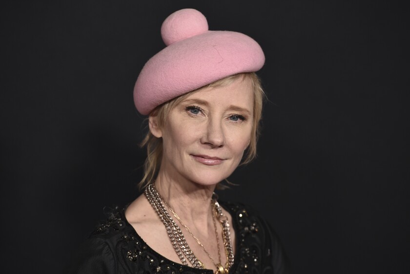 A woman with short hair and a pink beret smiles