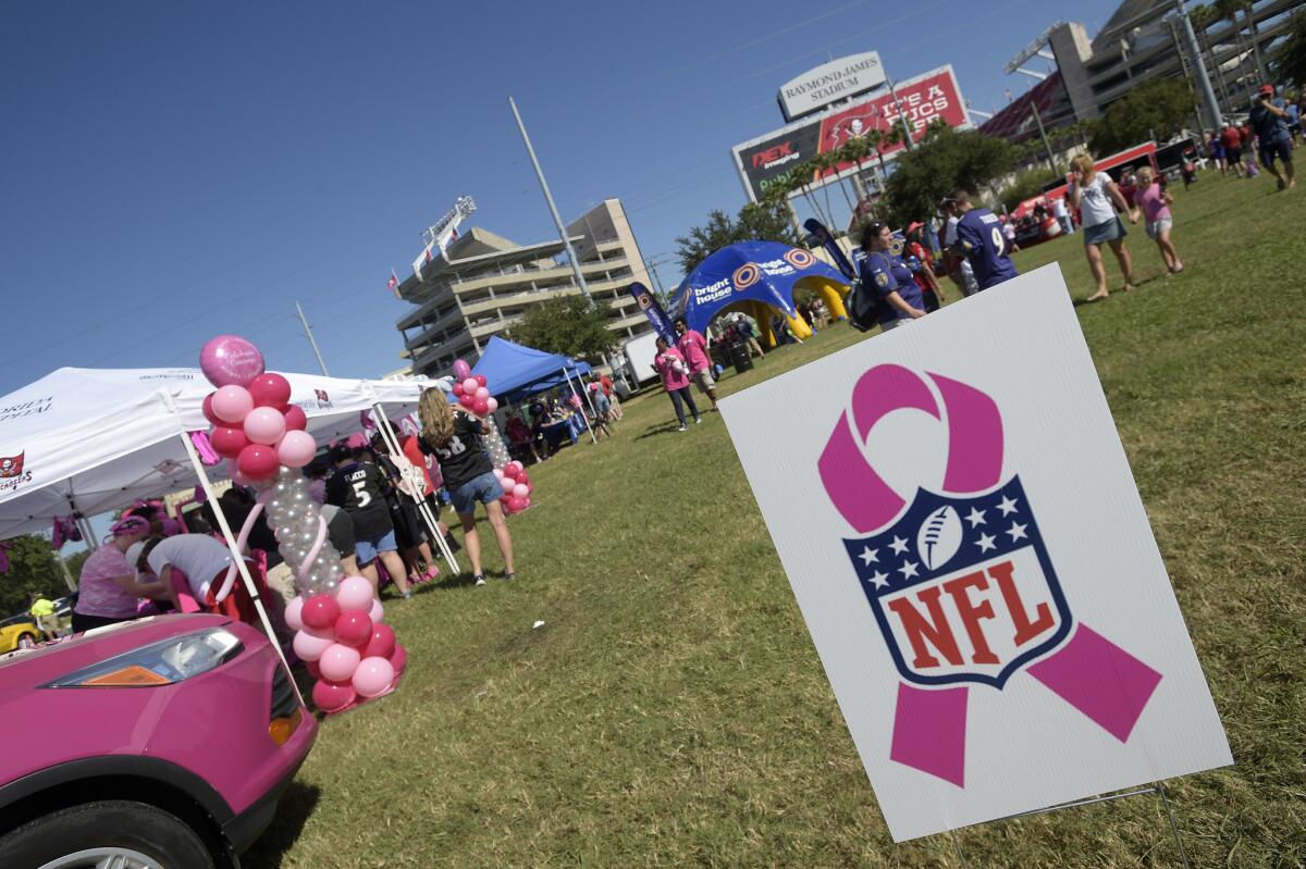 A pink ribbon sign showing support for Breast Cancer Awareness Month stands in a fan area outside the stadium before an NFL football game between the Tampa Bay Buccaneers and Baltimore Ravens in Tampa, Fla.