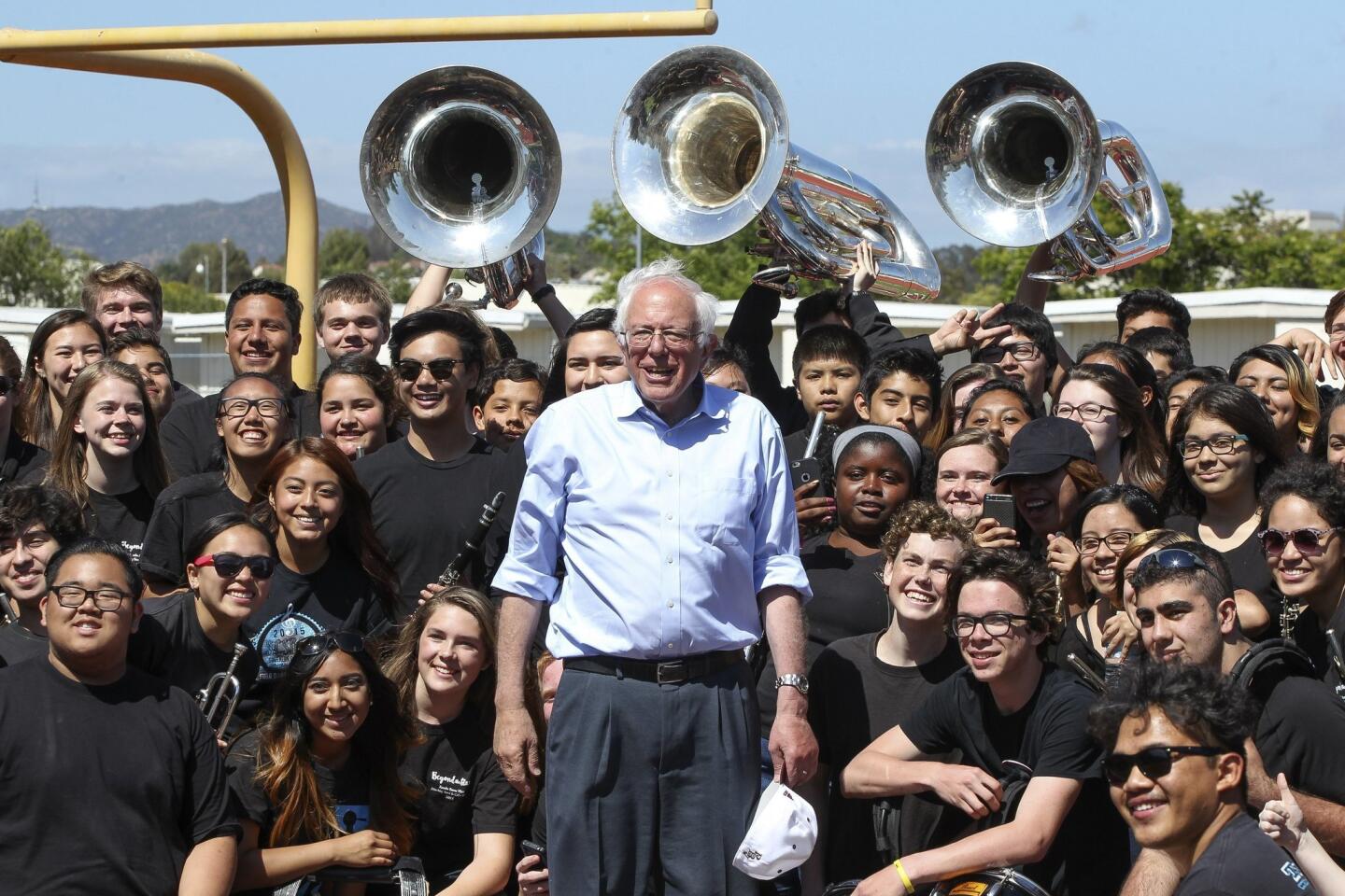 After speaking at his campaign rally in the Rancho Buena Vista High School football stadium, Democratic presidential candidate Bernie Sanders poses for pictures with members of the school's marching band.