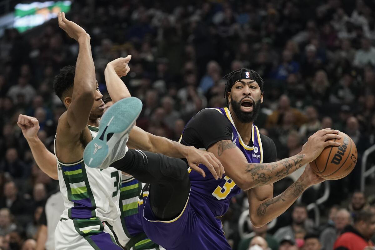 The Lakers' Anthony Davis grabs a rebound in front of the Bucks' Giannis Antetokounmpo 