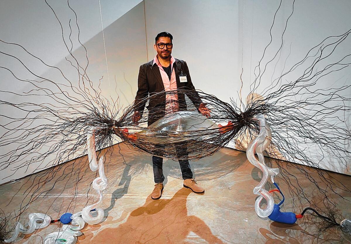 Glass artist Hugo Heredia Barrera, with his supersized cancer-infected cell, trapped in steel threads and connected by plastic DNA tubes to some still-healthy, clear-glass cells. 'Illumination: 21st century interactions with art, science and technology' is on exhibit through May 3, 2020 at San Diego Art Institute, 1439 El Prado in Balboa Park, San Diego. Hours: noon to 5 p.m. Tuesday-Sunday. (619) 236-0011. sandiego-art.org