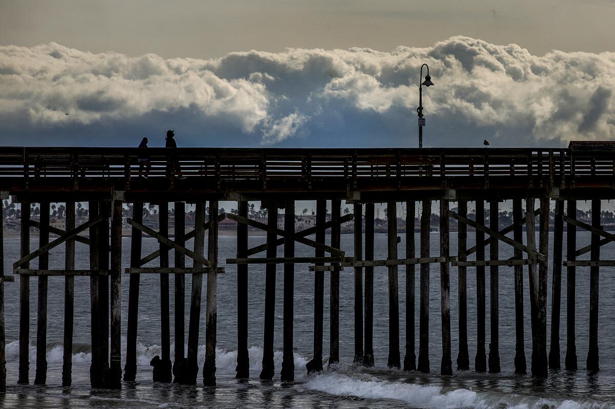 A pier extending out into the ocean with clouds in the background.