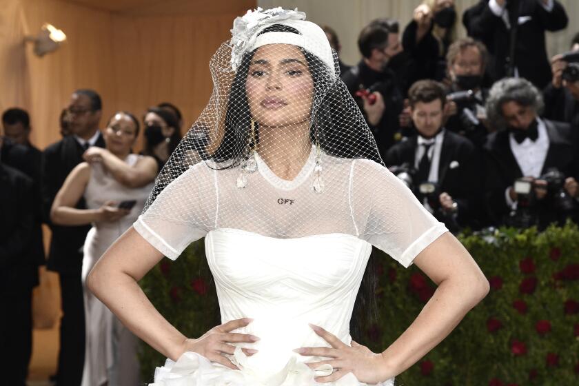 A woman in a white veil and baseball cap posing with her hands on her hips