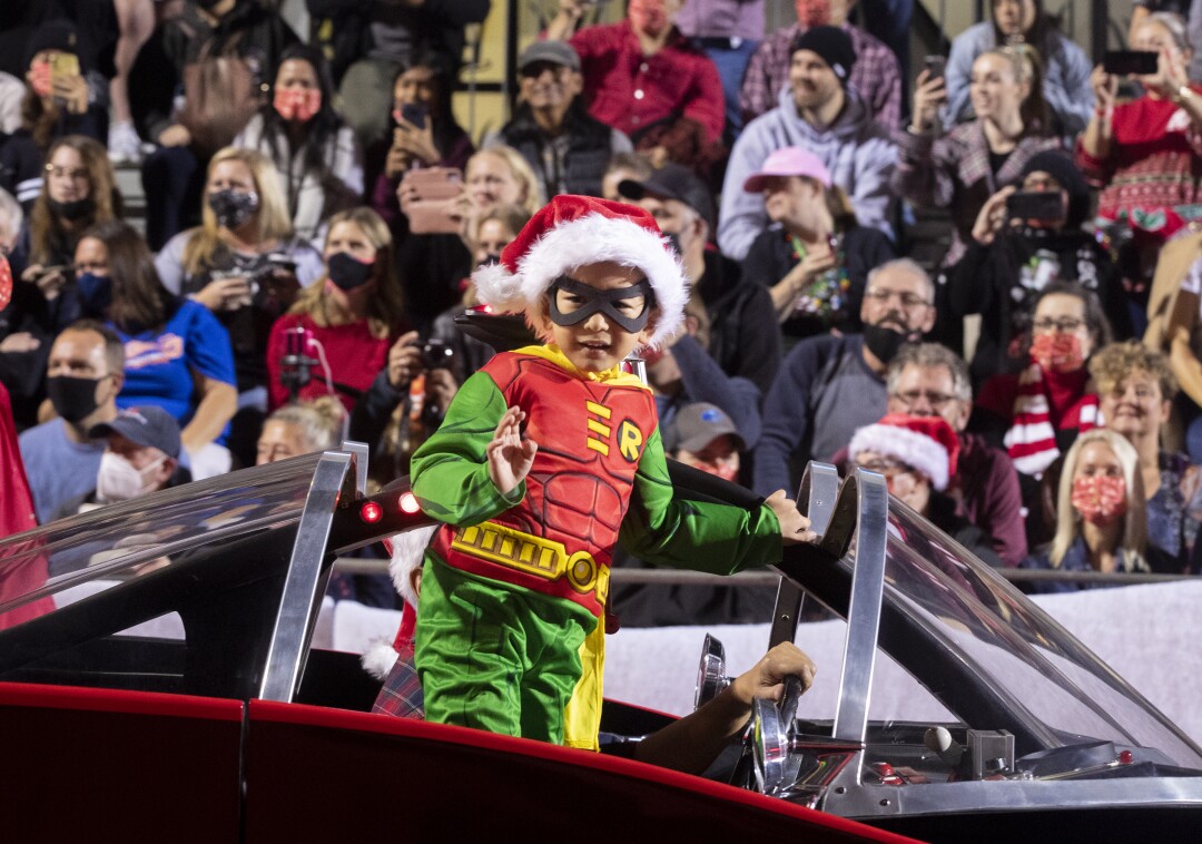 A young boy dressed as Robin rides in a Batmobile at the Christmas parade