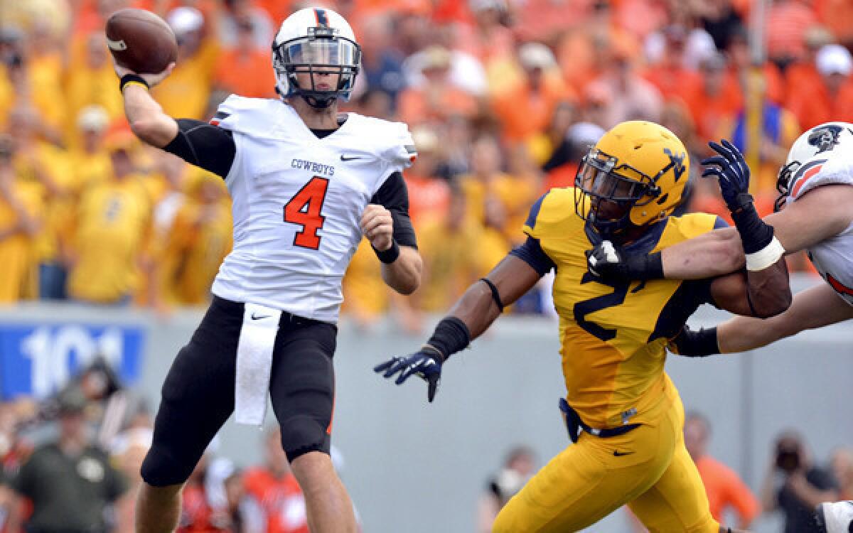 Oklahoma State quarterback J.W. Walsh gets off a pass under pressure from West Virginia linebacker Brandon Golson in the second quarter Saturday.