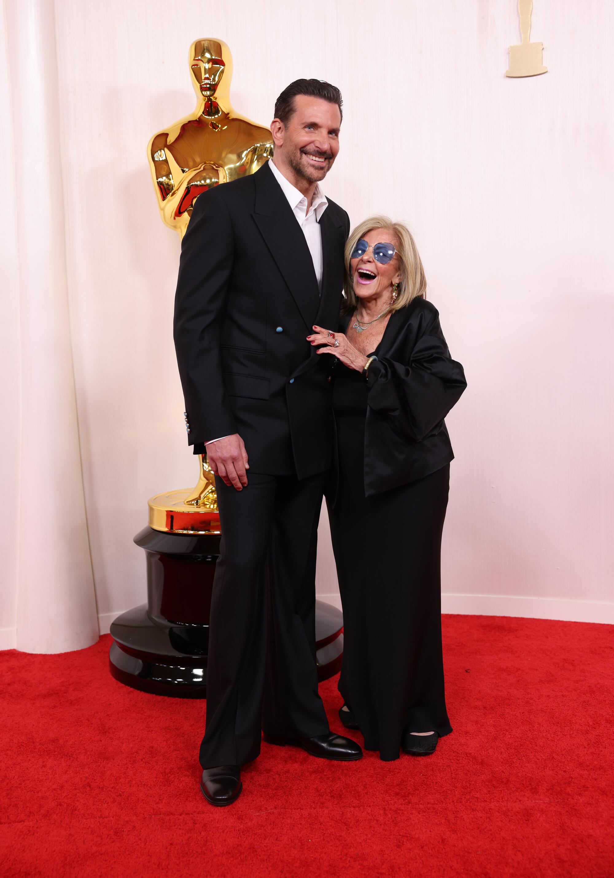 Bradley Cooper and Gloria Campano laugh on the red carpet. 