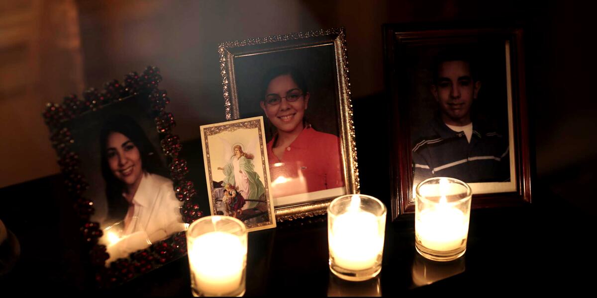 Lit candles sit next to framed photos of young people 