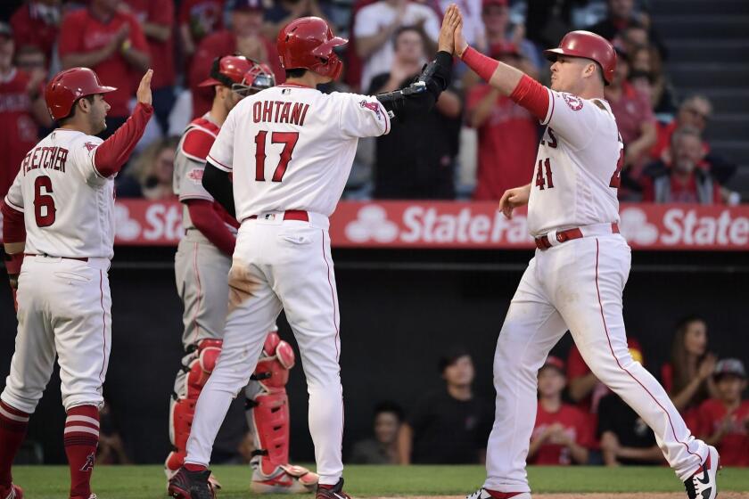 Los Angeles Angels' Justin Bour, right, is congratulated by Shohei Ohtani (17) and David Fletcher, left, as Cincinnati Reds catcher Curt Casali stands at the plate during the eighth inning of a baseball game Wednesday, June 26, 2019, in Anaheim, Calif. (AP Photo/Mark J. Terrill)