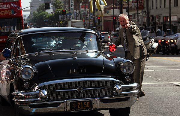 Councilman Tom LaBonge directs a vintage 1955 Buick police car
