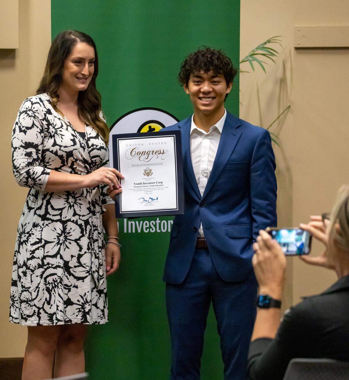 Dylan Jin-Ngo, right, is presented with a certificate of recognition for his dedication to financial literacy education.