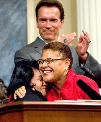 Assemblywoman Karen Bass (D-Los Angeles) hugs stepdaughter Yvette Lechuga as Gov. Arnold Schwarzenegger applauds. Bass was sworn in Tuesday as speaker of the California Assembly at the Capitol in Sacramento. Elected to the Assembly in 2004, she is the first African American woman to serve as its speaker.