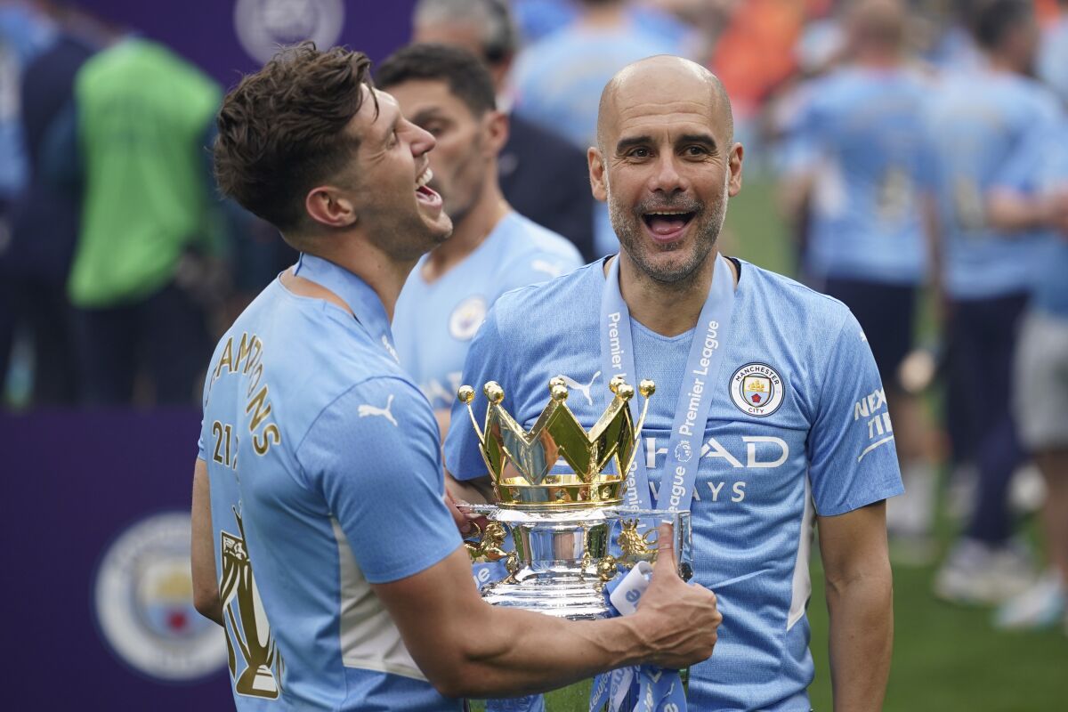 ARCHIVO - El técnico del Manchester City, Pep Guardiola, derecha, sonría frente al trofeo 