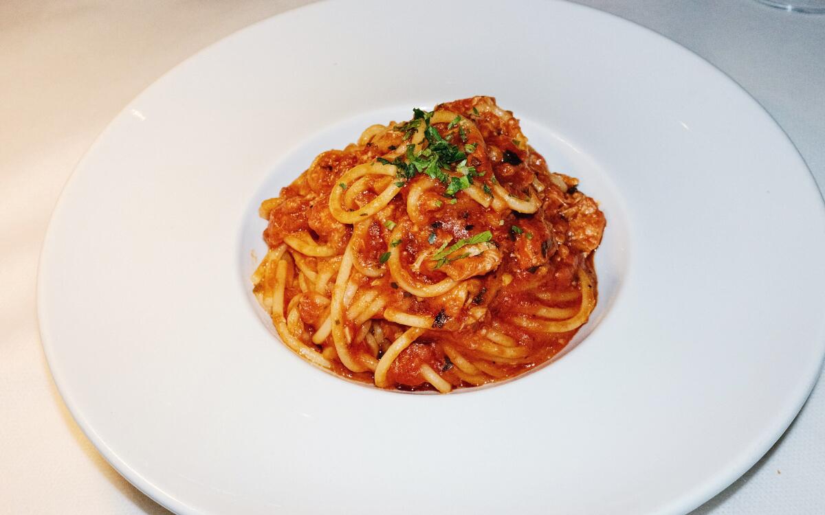 A small mound of spaghetti in tomato sauce in a white bowl on a white tablecloth at Osteria Mamma.