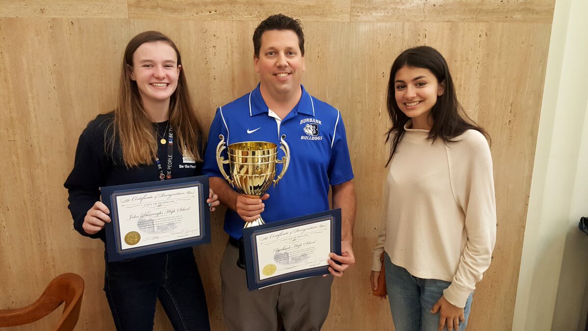 Burroughs High School seniors Alyssa LeBarron, left, and Arya Desai, right, were presented with a certificate of achievement for their voter-registration efforts last month during the city’s annual Clerk’s Cup competition on Dec. 17 at Burbank City Hall. The duo registered or pre-registered 57 students. Once again, however, Burbank High School was the champion as economics teacher Doug Grimshaw, center, hoisted the cup after the school registered or pre-registered 146 students.