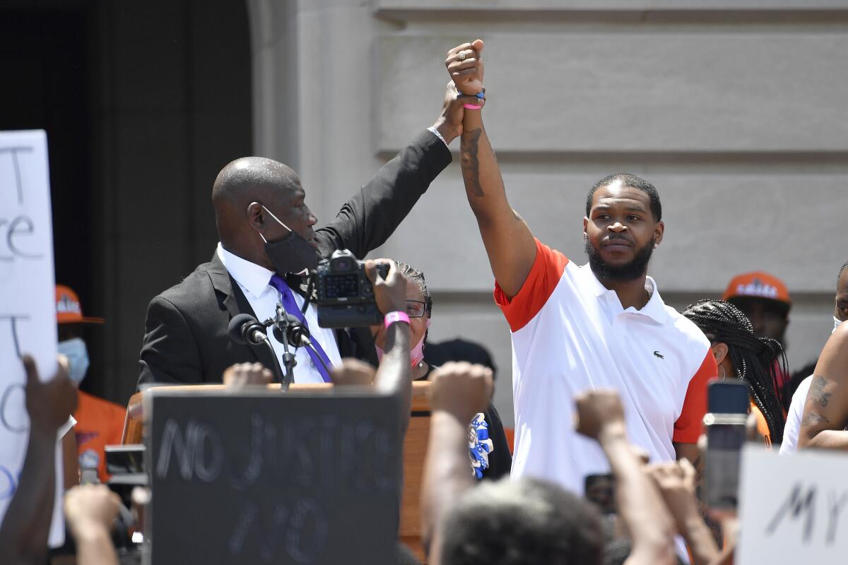 Attorney Benjamin Crump, left, holds up the hand of Kenneth Walker during a rally on the steps of the Kentucky State Capitol in Frankfort, Ky., Thursday, June 25, 2020. Walker was the boyfriend of Breonna Taylor who was killed by officers of the Louisville Metro Police Department following the execution of a no knock warrant on her apartment on March 13, 2020. (AP Photo/Timothy D. Easley)