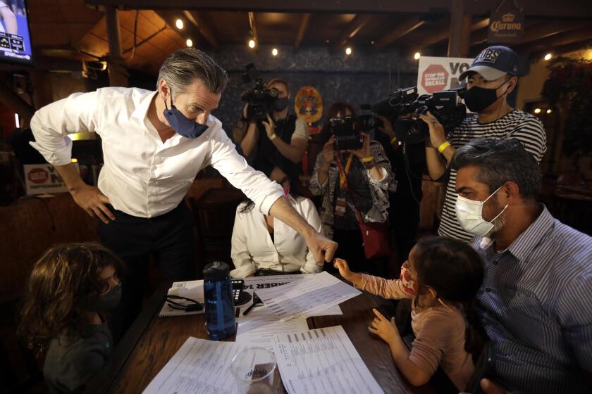 EAST LOS ANGELES, CA - AUGUST 14, 2021 - -California Gov. Gavin Newsom greets Frida Carrillo, 4, and her father Franky, and thanks them for working the phone banks against the governor's recall at Hecho en Mexico restaurant in East Los Angeles on August 14, 2021. Los Angeles City Councilman Kevin de Leon, California State Senator Maria Elena Durazo, California Assemblyman Miguel Santiago and other Latino dignitaries were on hand to support the governor. (Genaro Molina / Los Angeles Times)