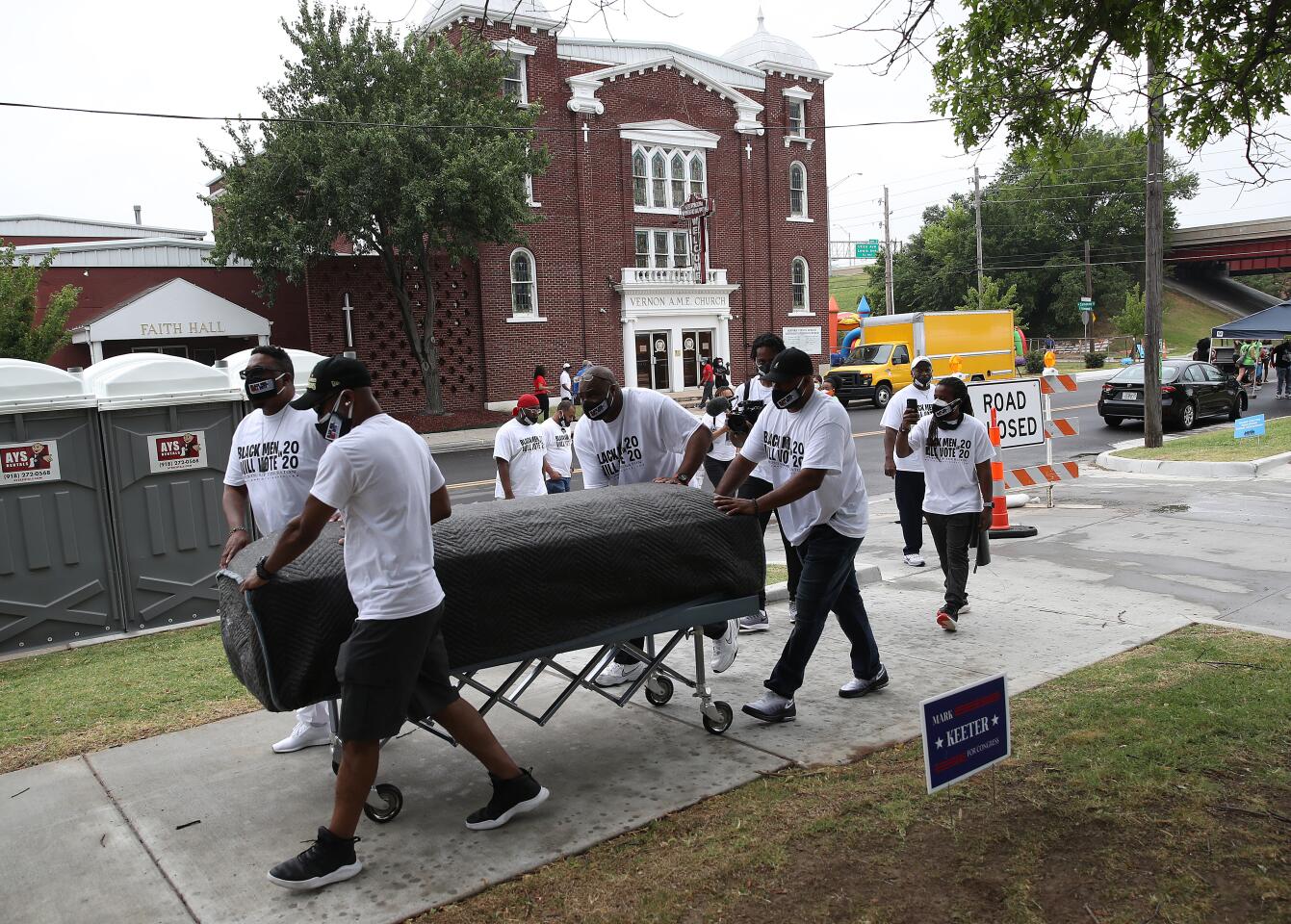 People push an empty symbolic casket during a Juneteenth event in the Greenwood District of Tulsa.
