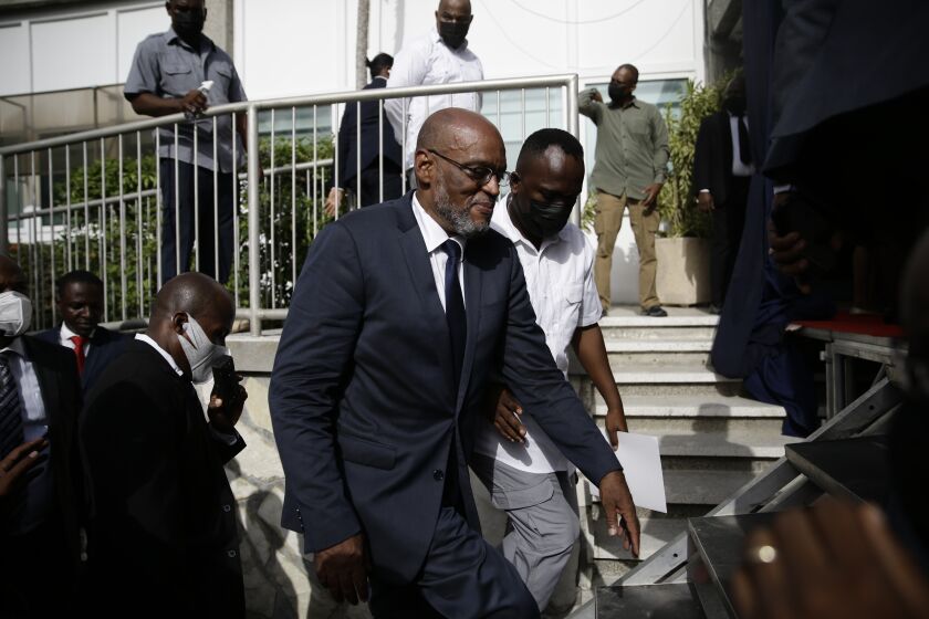 New Prime Minister Ariel Henry walks up a set of stairs escorted by his security detail after after his appointment in Port-au-Prince, Haiti, Tuesday, July 20, 2021, weeks after the assassination of President Jovenel Moise at his home. (AP Photo/Joseph Odelyn)