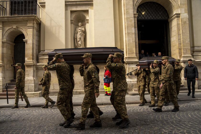 Soldiers carry the coffins of two Ukrainian army sergeants during their funeral in Lviv, Ukraine, Tuesday, April 16, 2024. (AP Photo/Francisco Seco)