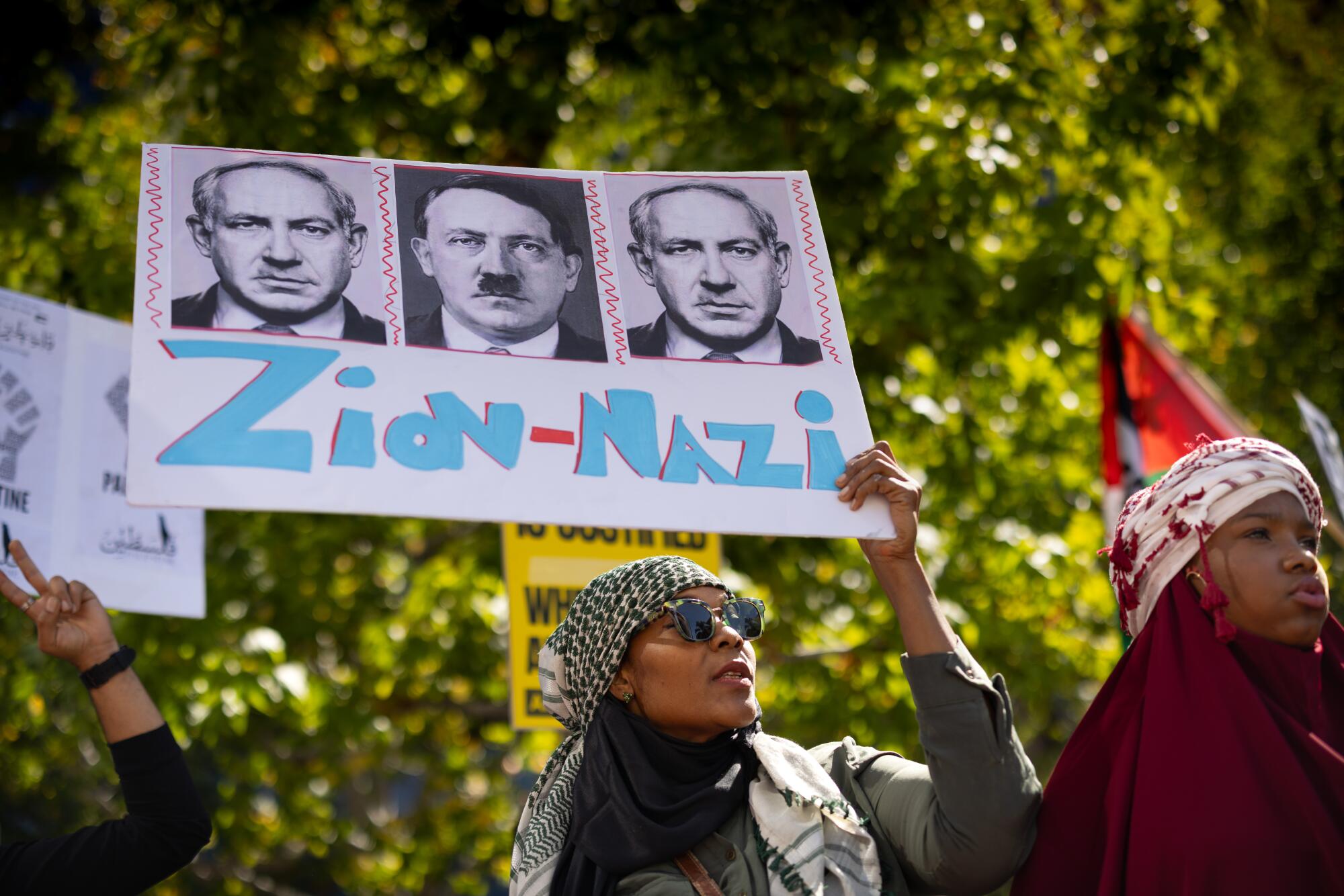 A woman holds up a sign with images of Hitler and Israel's Benjamin Netanyahu.