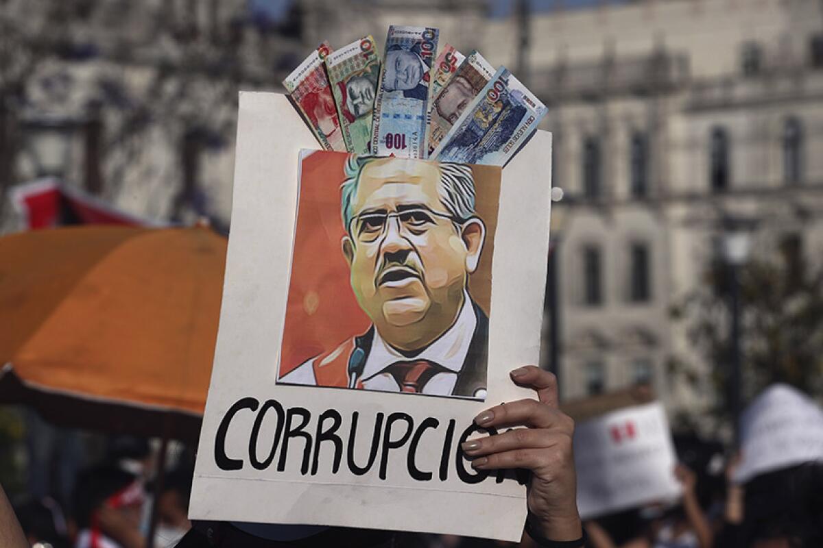 A protester holds an image of Peruvian leader Manuel Merino with the Spanish word for "corruption."