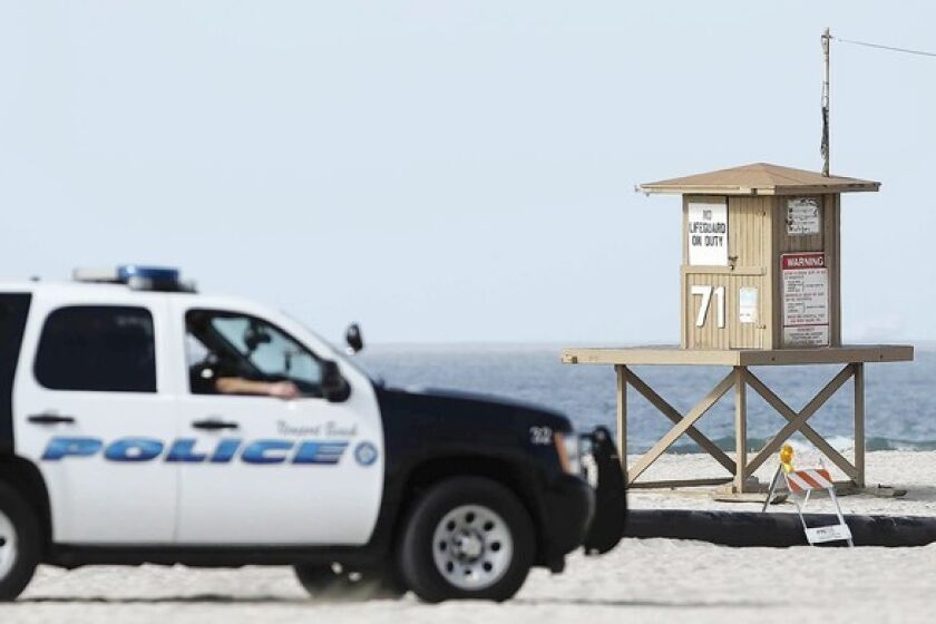 A Newport Beach police vehicle drives by Tower 71, where a dead body was found on Monday morning.