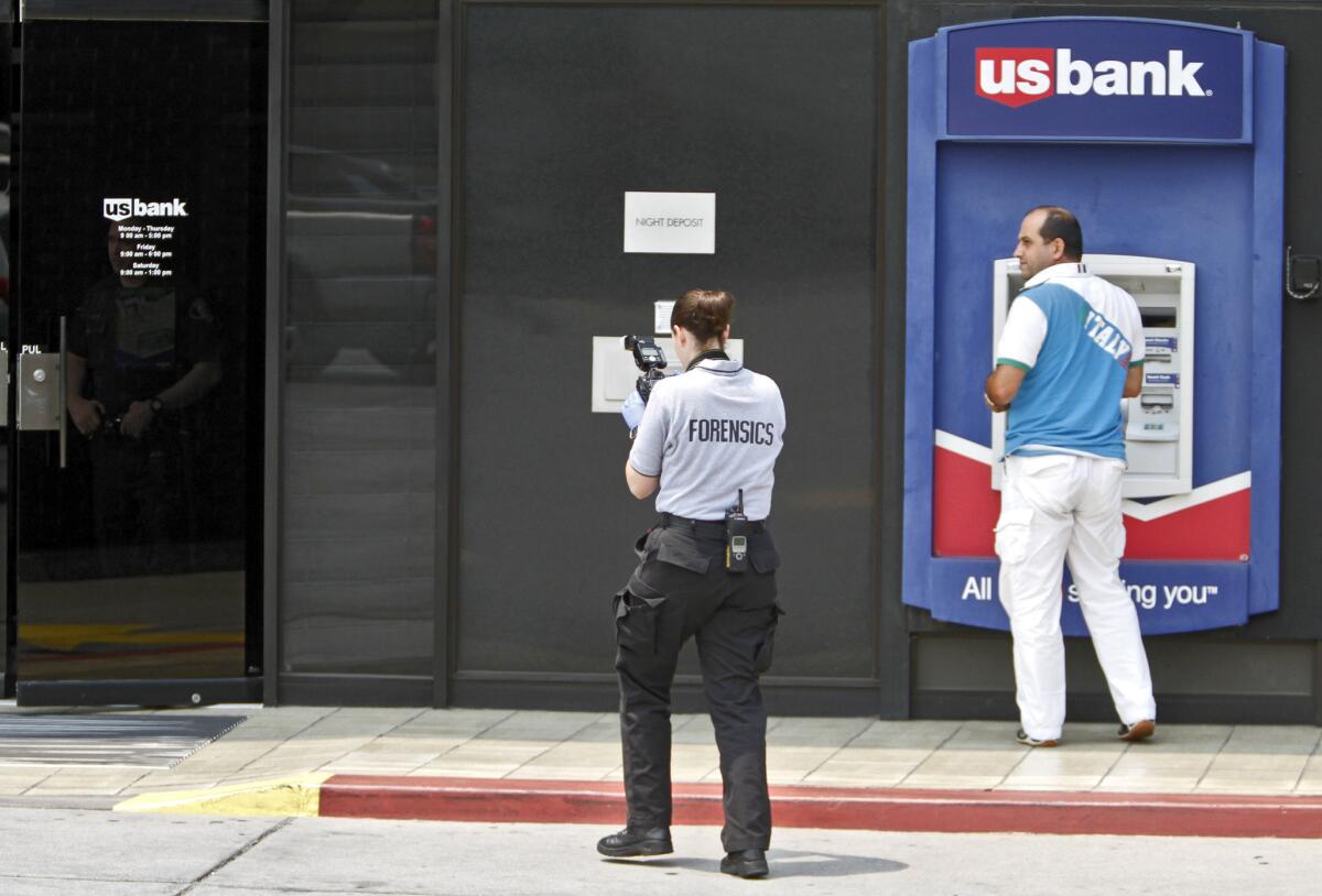 Customers could only use the ATM at the U.S. Bank on the 600 block of N. Brand Blvd. after a bank robbery took place on Tuesday, July 29, 2014. A member of the Glendale Police Dept. Forensics team takes photos outside the bank.