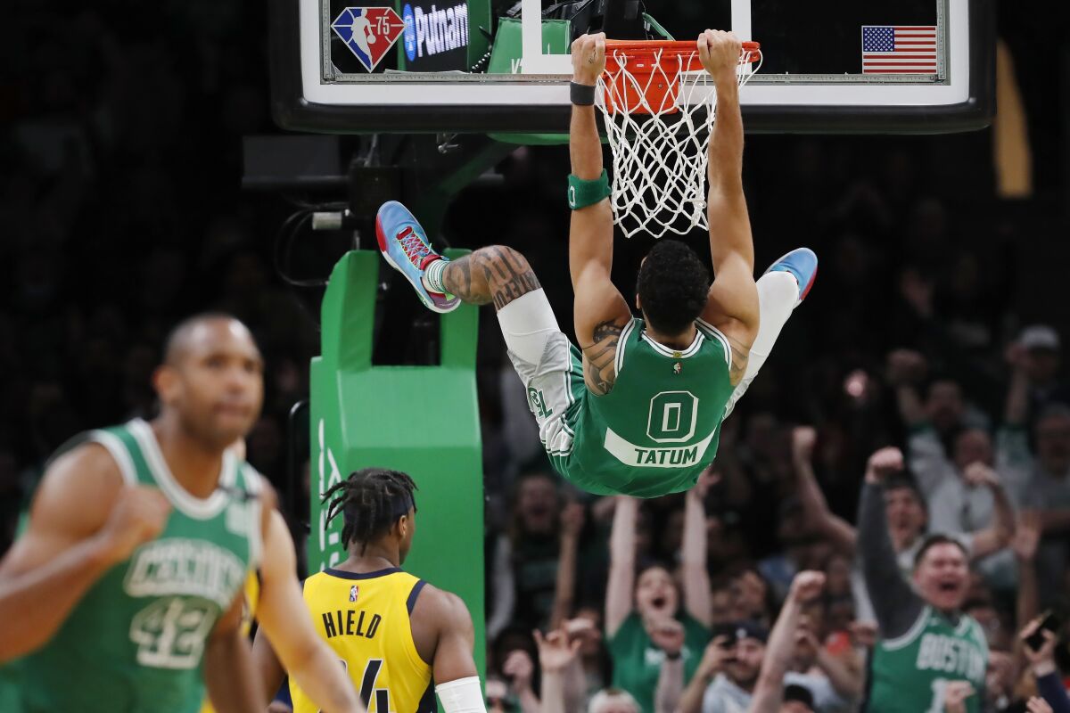 Boston Celtics' Jayson Tatum (0) hangs from the rim after a dunk during the second half of the team's NBA basketball game against the Indiana Pacers, Friday, April 1, 2022, in Boston. (AP Photo/Michael Dwyer)