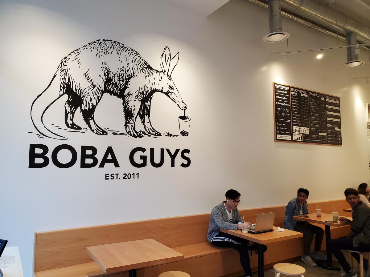 people sit at tables inside a Boba Guys bubble tea location