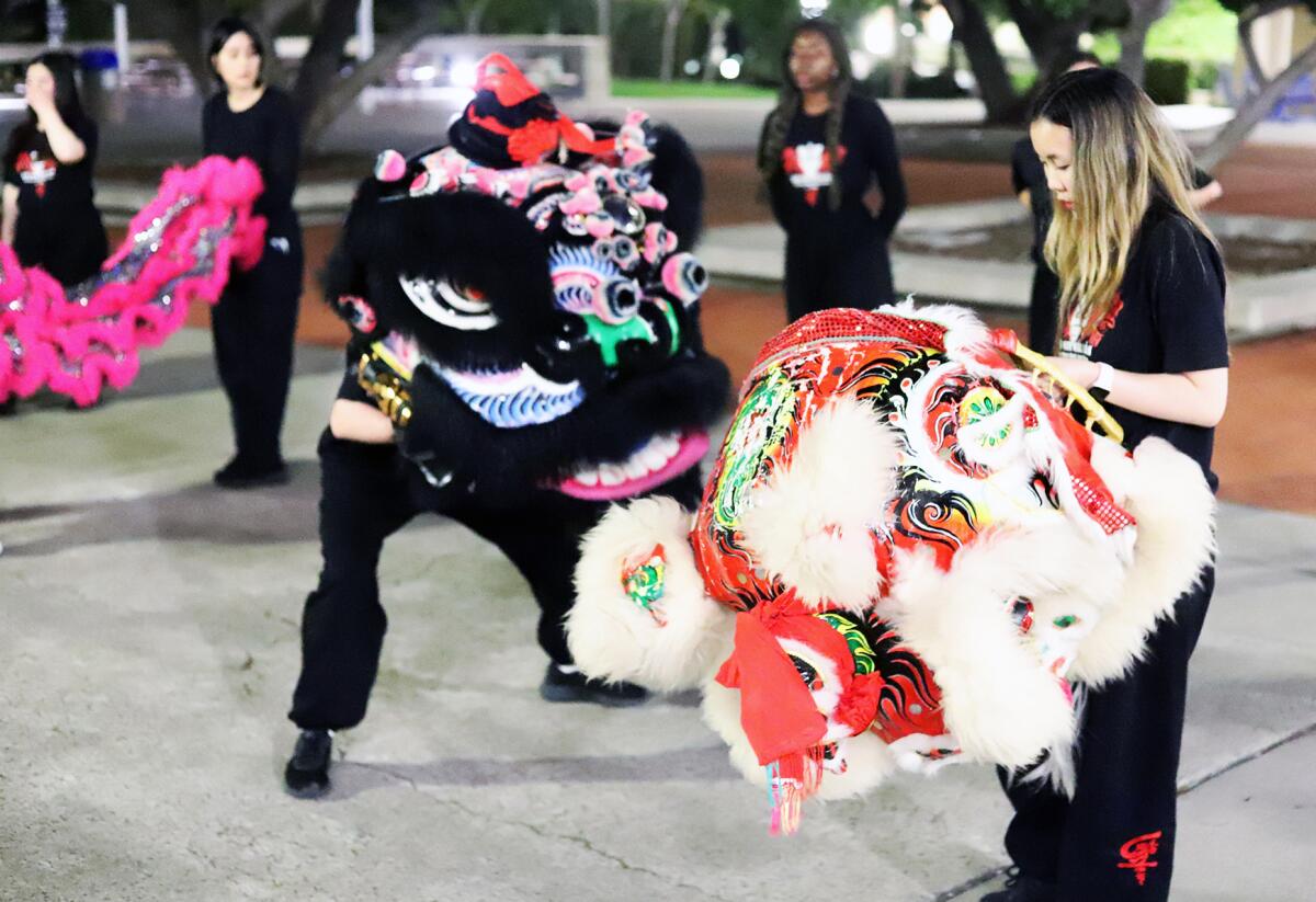 Sasha Lin, 19, a student at UC Irvine, right, takes a turn wearing the lion head.