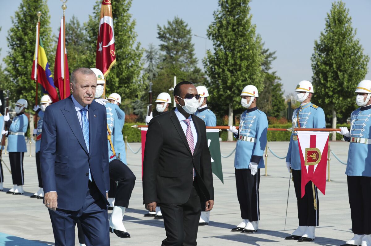 Turkish President Recep Tayyip Erdogan, left, and Ethiopian Prime Minister Abiy Ahmed review a military guard of honour in Ankara, Turkey, Wednesday, Aug. 18, 2021. Erdogan urged Wednesday a peaceful resolution of the Tigray conflict in Ethiopia and also said his country was willing to mediate between Addis Ababa and Sudan for a resolution of a border dispute.(Turkish Presidency via AP, Pool)