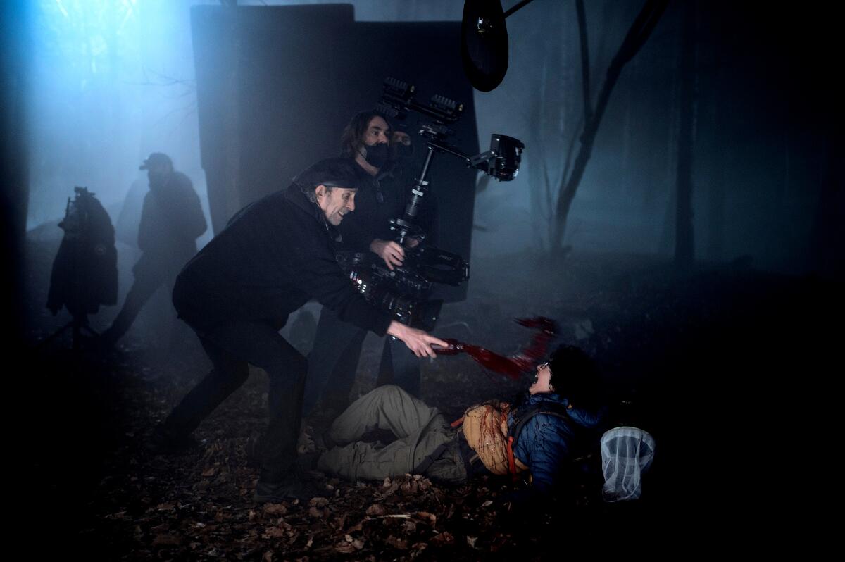 A night shoot for "Wednesday" in the dark forest has a young teen screaming on the ground with a camera crew over him.