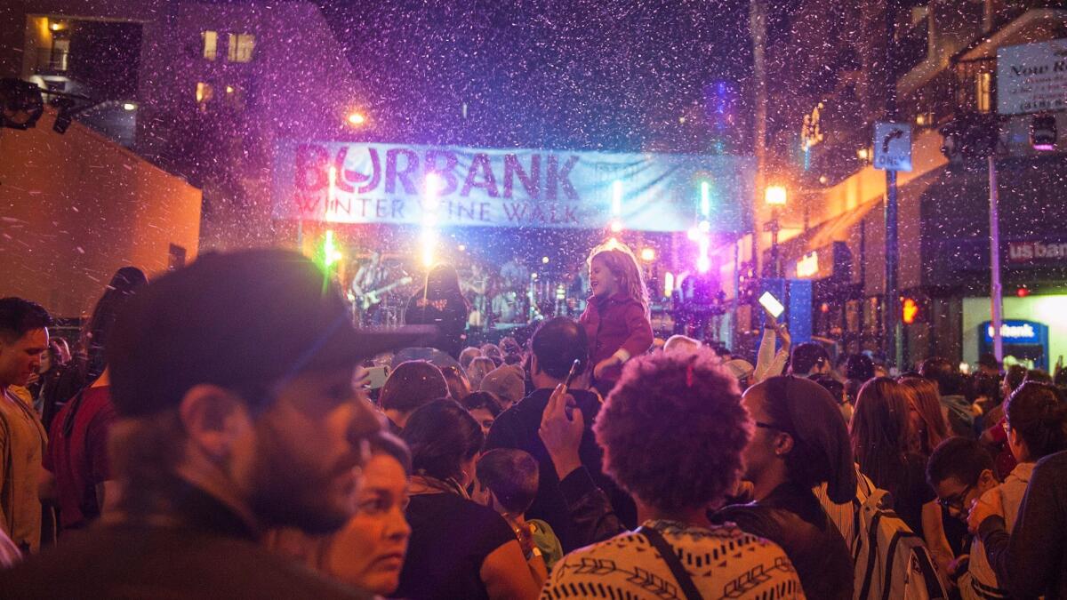 An artificial snowfall hits the intersection of Palm and San Fernando as Adelaide performs during the second annual Winter Wine Walk in downtown Burbank on Saturday.