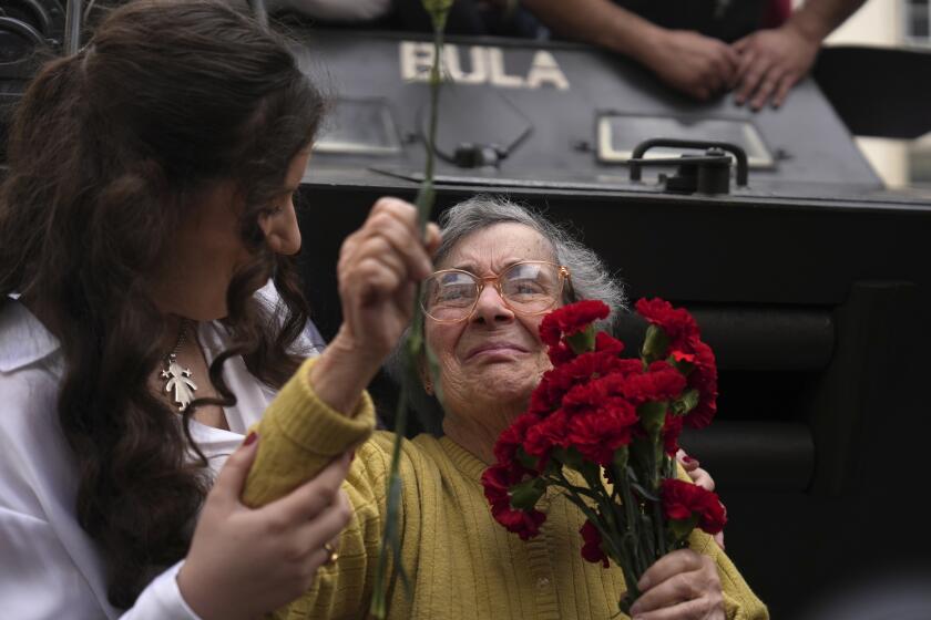 Celeste Caeiro, de 90 años, sostiene un ramo de claveles en Lisboa, Portugal, el jueves 25 de abril de 2024, en la recreación del movimiento de tropas de hace 50 años, como parte de las celebraciones por el aniversario de la Revolución de los Claveles. (AP Foto/Ana Brigida)