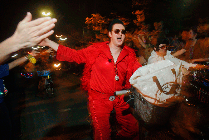 A member of the Krewe of Rolling Elvi, a local group who loves to dressed as Elvis Presley, rides a motorbike during the Muses Mardi Gras parade.