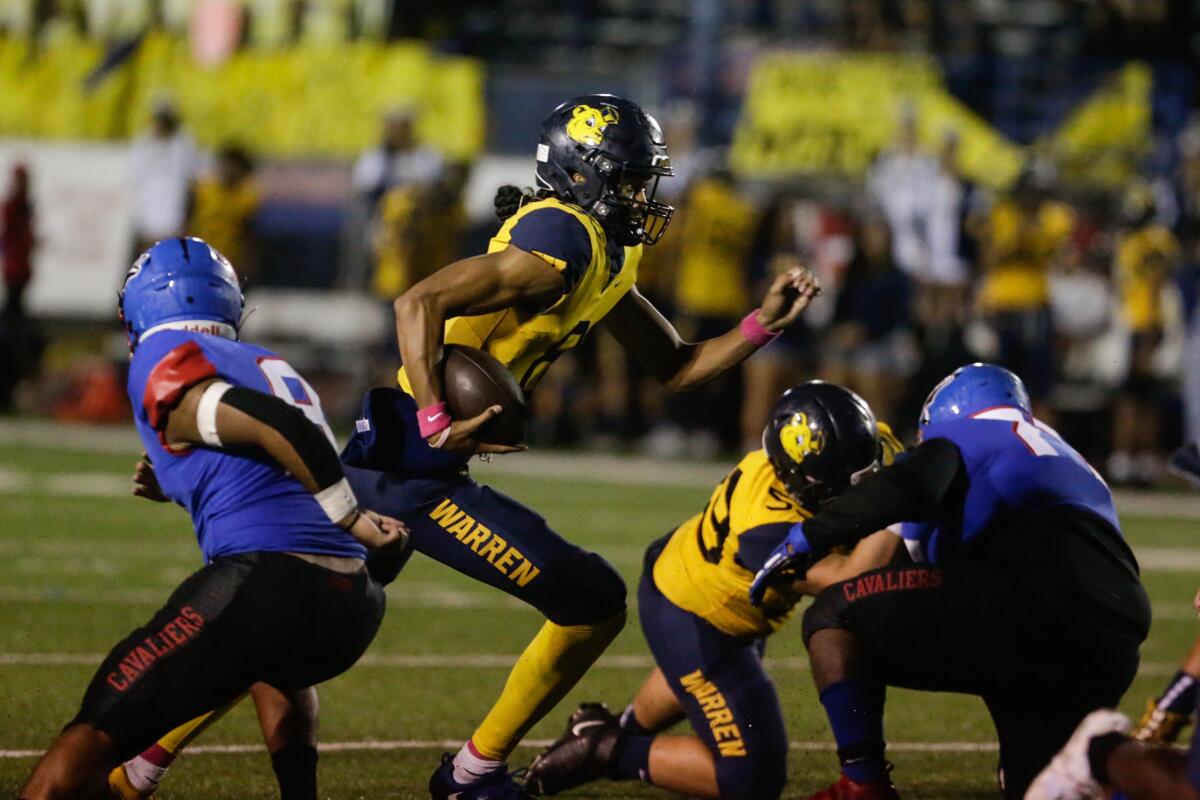 Warren quarterback Nico Iamaleava cuts inside a block along the line of scrimmage.