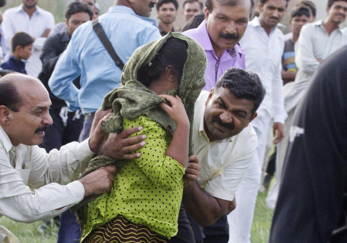 In this Sept. 8 file photo, a Pakistani police officer and a Christian volunteer escort a young Christian girl accused of blasphemy toward a helicopter following her release from central prison near Rawalpindi, Pakistan. A defense lawyer said Tuesday that a Pakistani court has acquitted the girl accused of burning pages from a Koran.