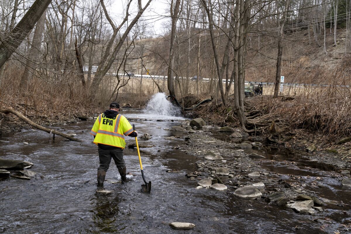 EPA official looks for signs of fish and also agitates the water in Leslie Run creek in East Palestine, Ohio.