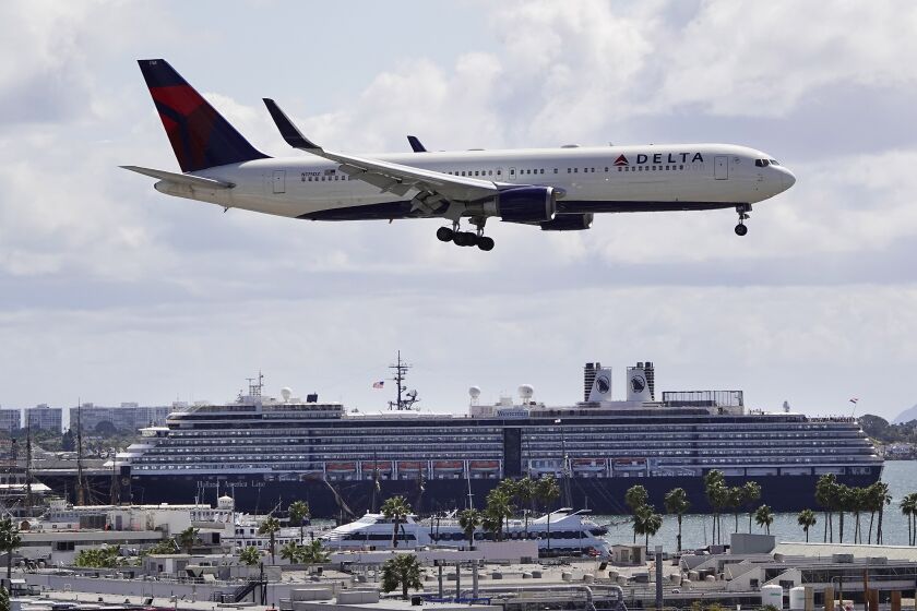 A Delta Airlines jet approaches San Diego International Airport as Holland America's MS Westerdam is docked in San Diego Bay on March 26, 2020.