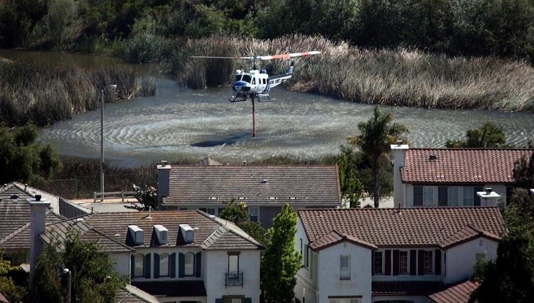 A helicopter picks up water from a reservoir in Newbury Park to fight the Springs fire.