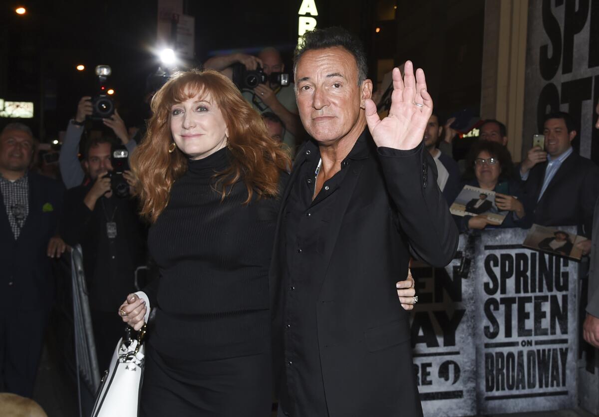 Patti Scialfa and Bruce Springsteen, both dressed in black, walking together out of his Broadway show and waving at fans